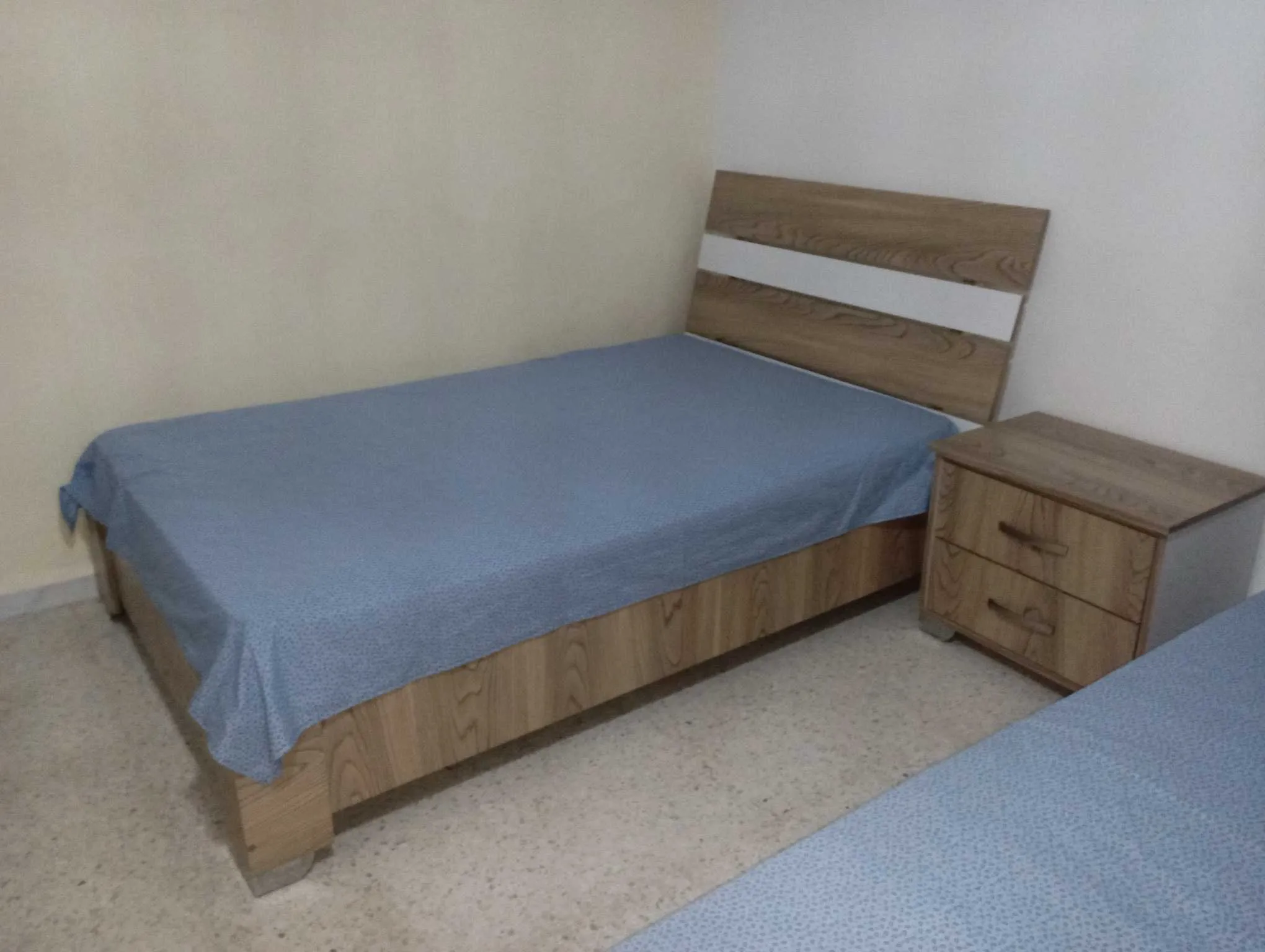 Deux lits avec matelas en bon état et une table de nuit