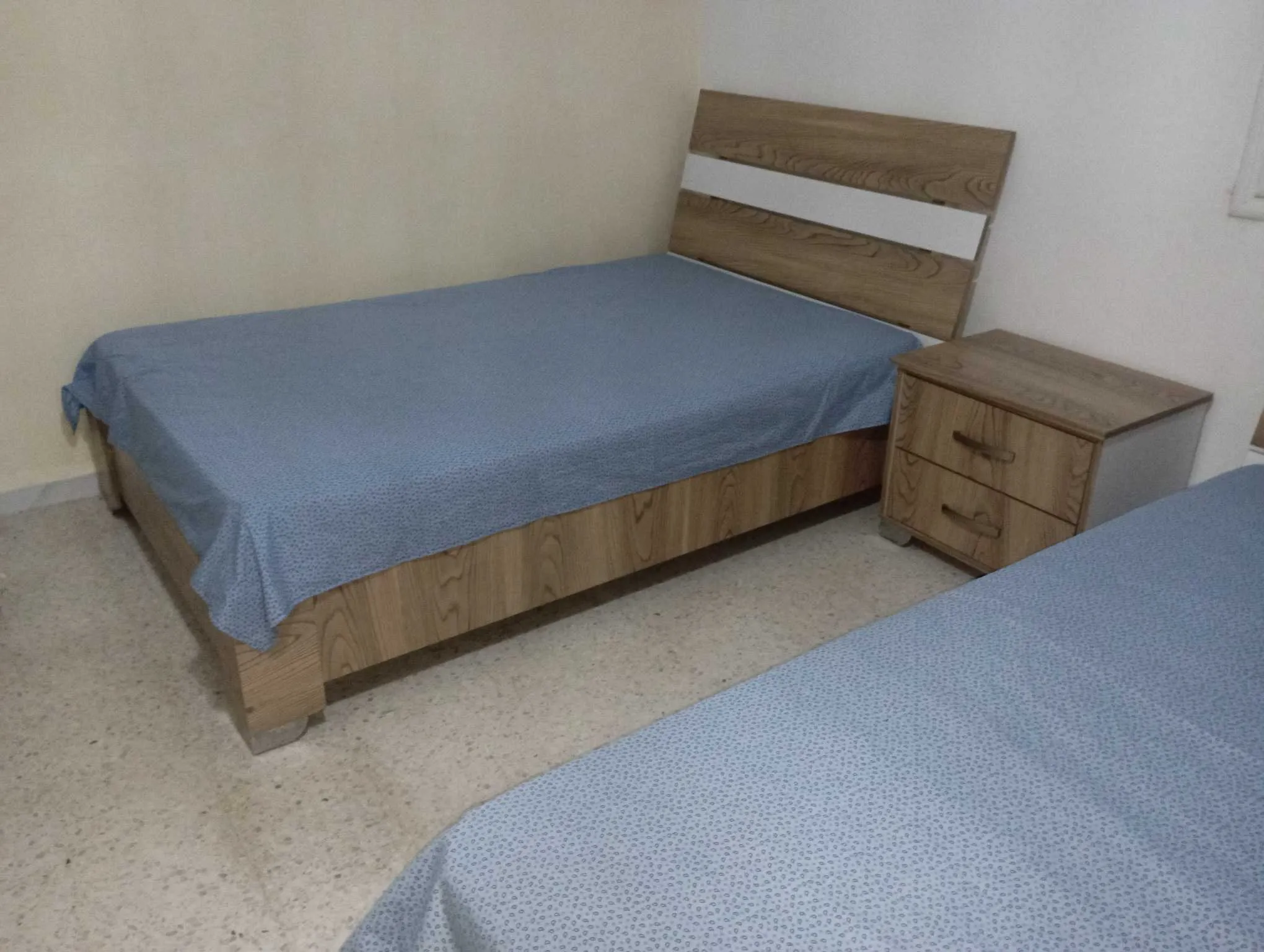 Deux lits avec matelas en bon état et une table de nuit