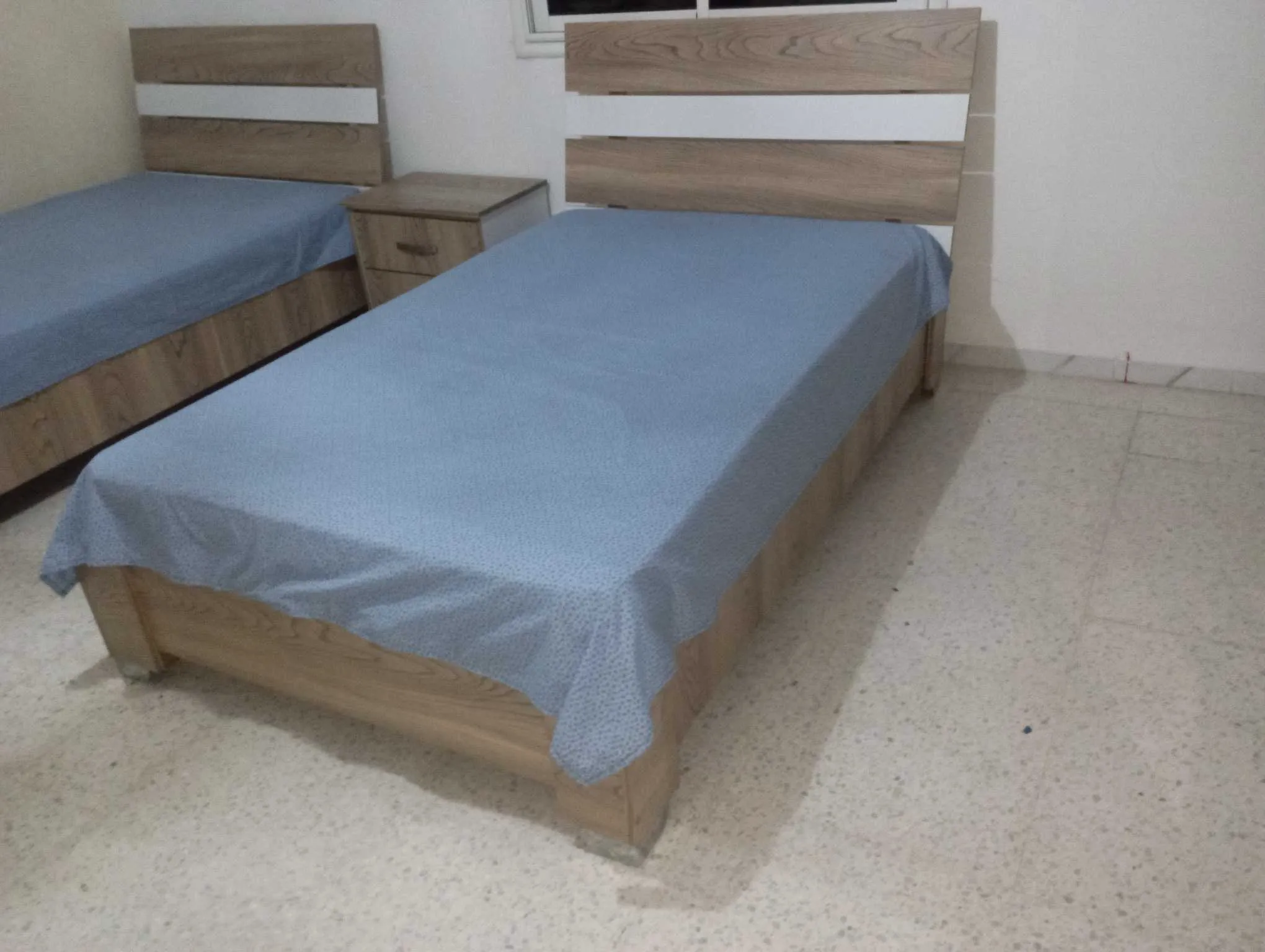 Deux lits avec matelas en bon état et une table de nuit