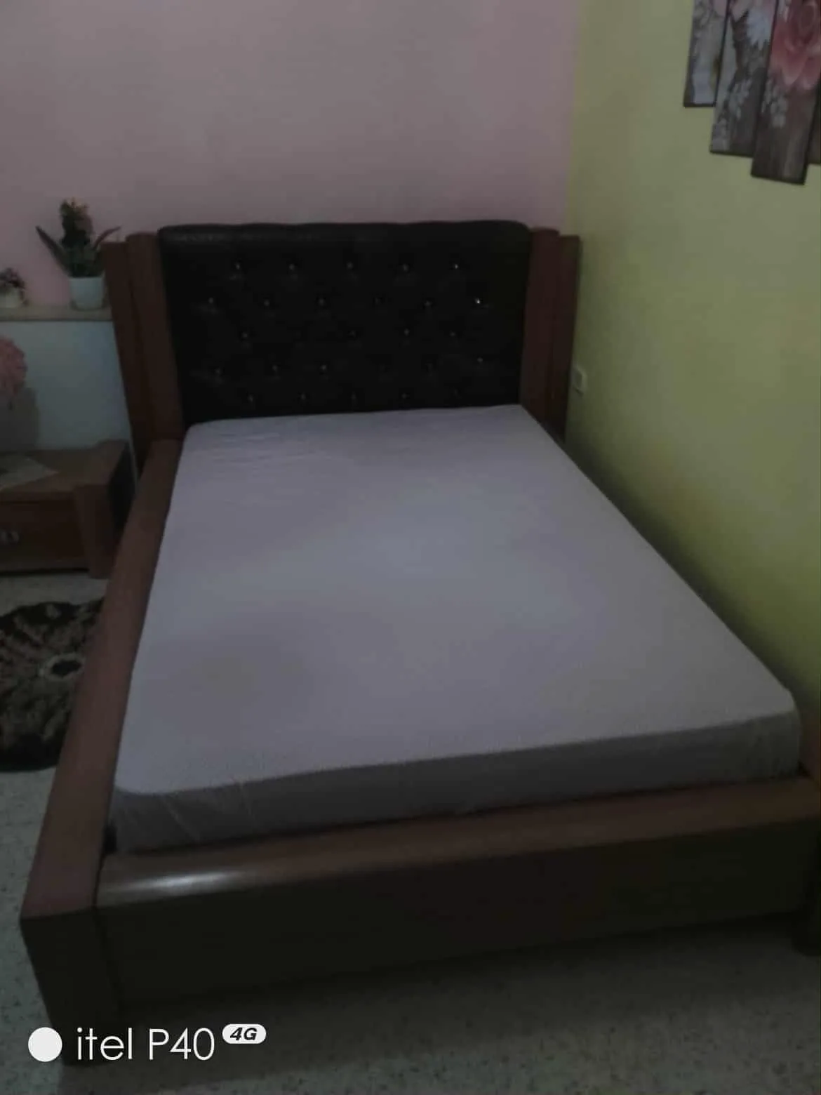 Un lit avec matelas en bon état et une table de nuit