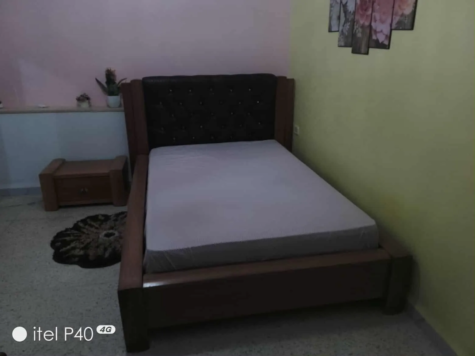 Un lit avec matelas en bon état et une table de nuit