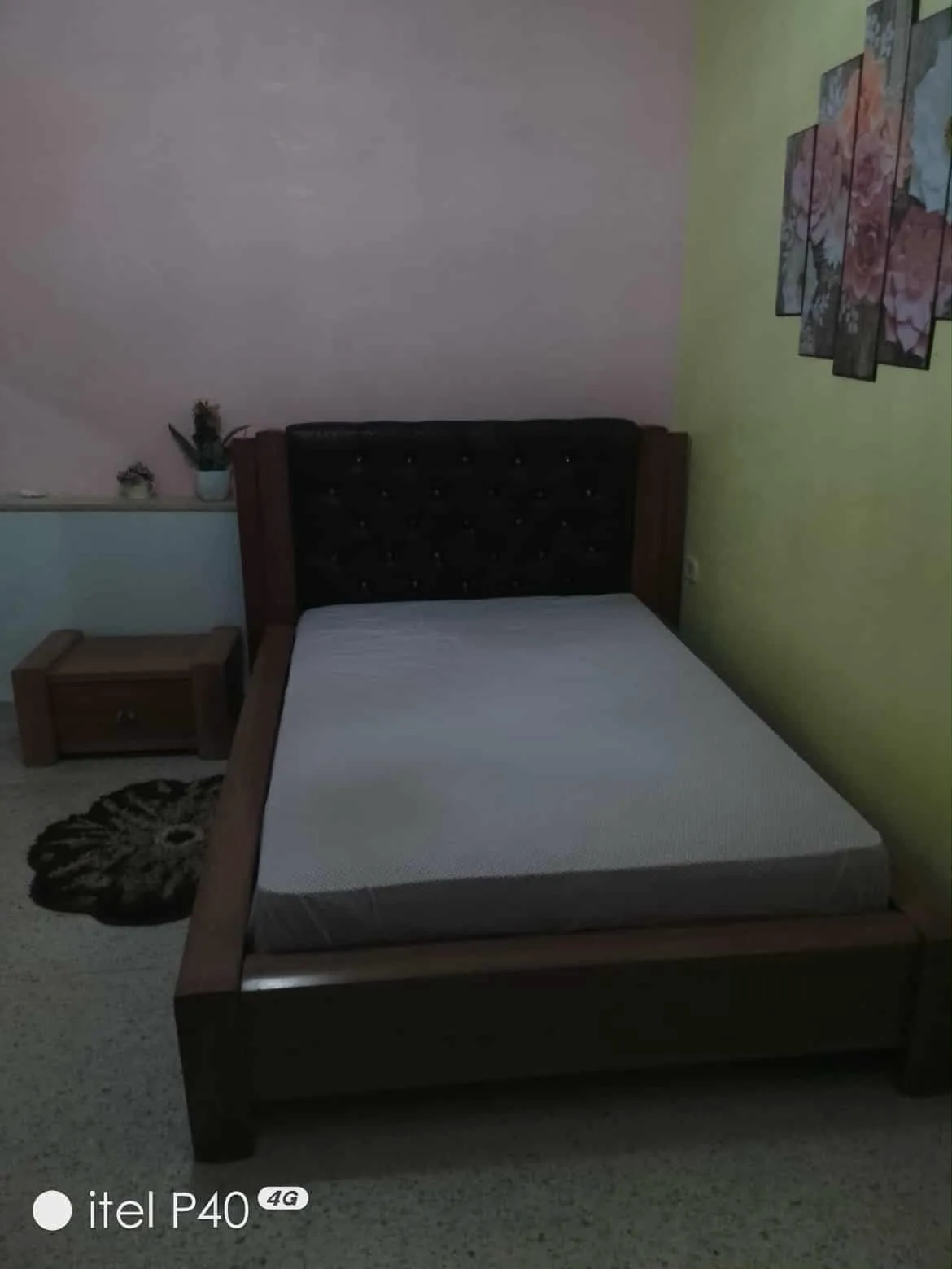 Un lit avec matelas en bon état et une table de nuit