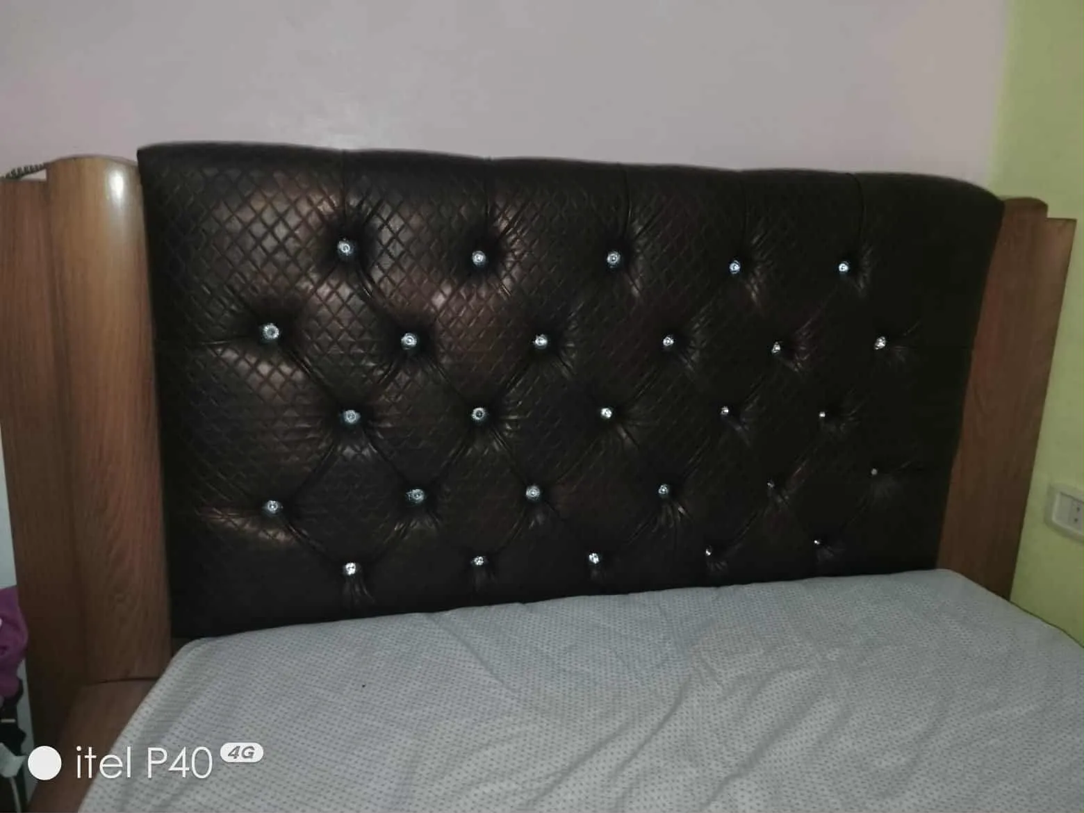 Un lit avec matelas en bon état et une table de nuit